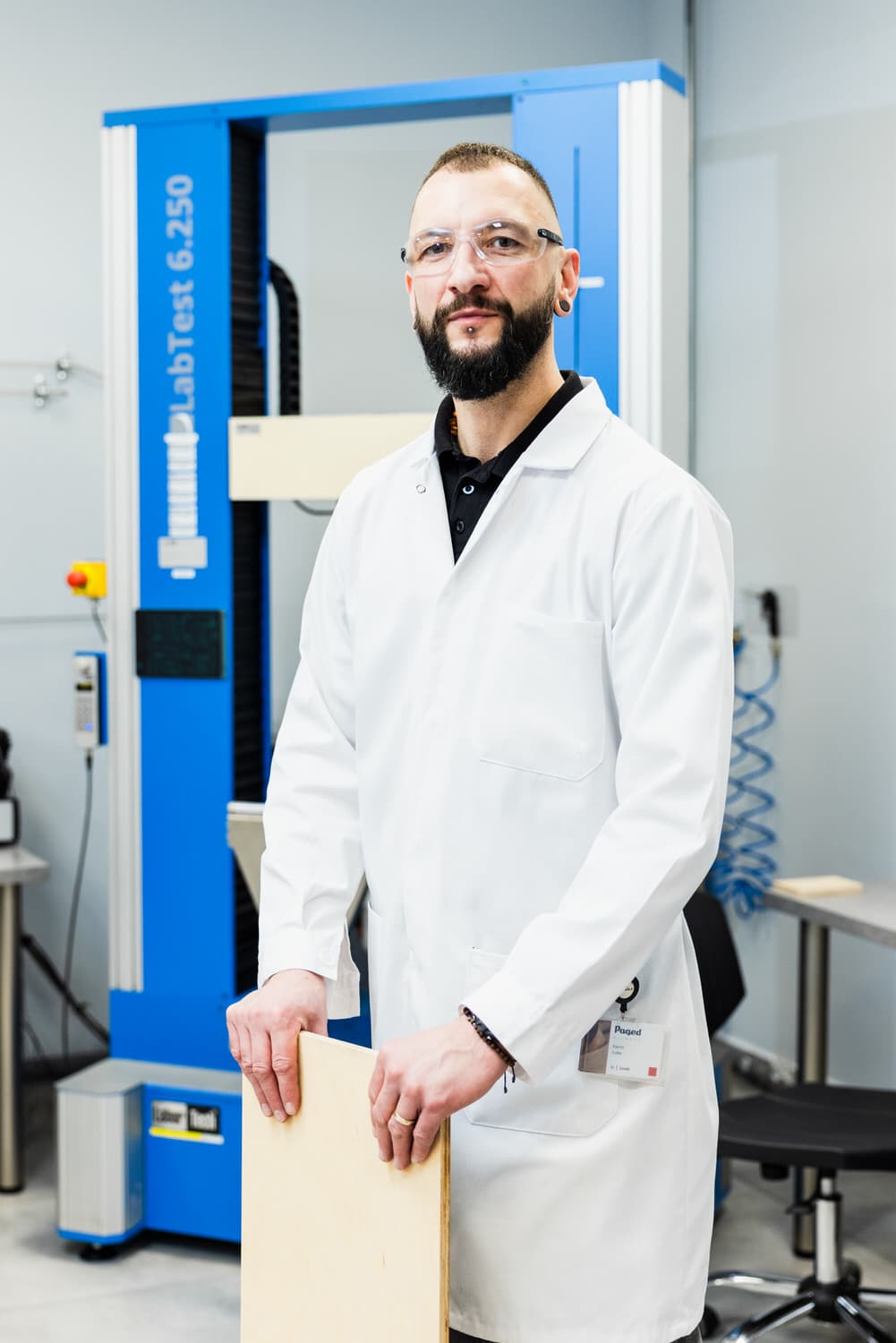 Laborspezialist mit einer Plattenprobe an der Universalprüfmaschine