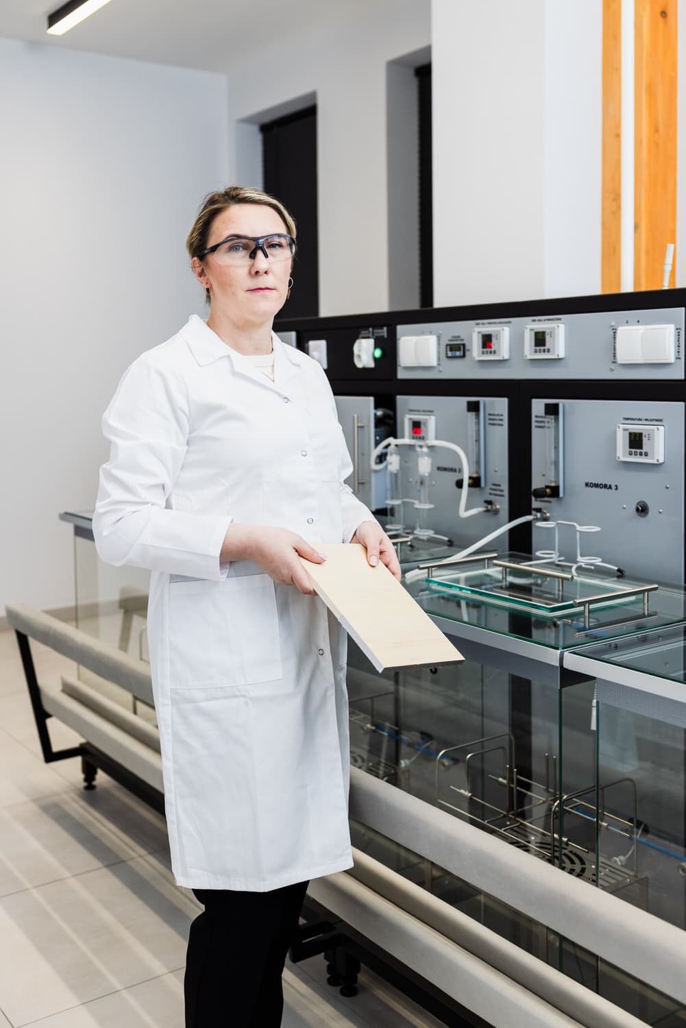 Laborspezialistin mit einer Plattenprobe an den Formaldehyd-Emissionskammern