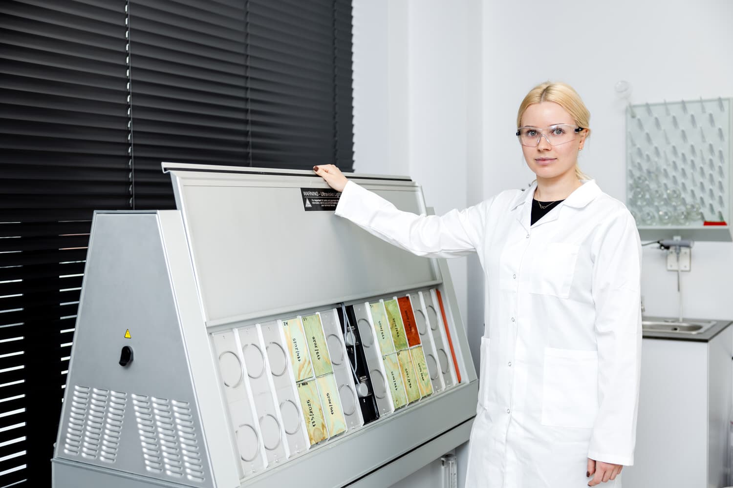 Specjalistka laboratorium przy komorze QUV z próbkami powłok