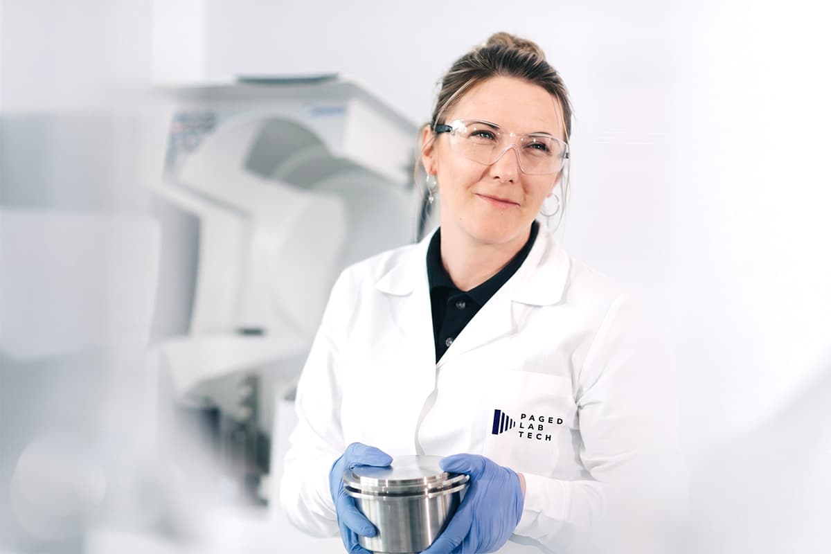 Specjalistka Paged LabTech w fartuchu laboratoryjnym trzyma metalową próbkę w laboratorium badawczym